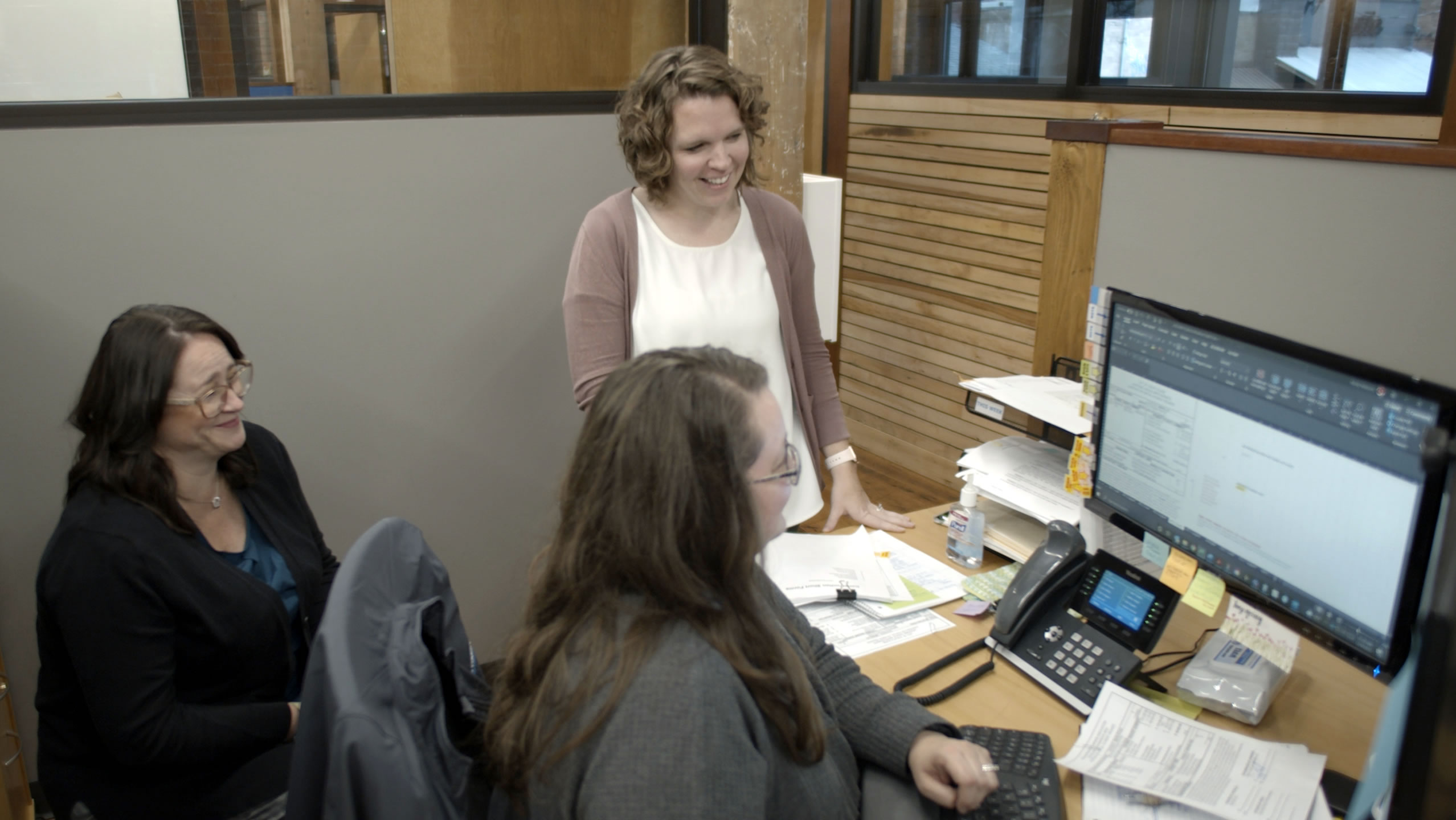 three employees reacting positively to information on a computer screen